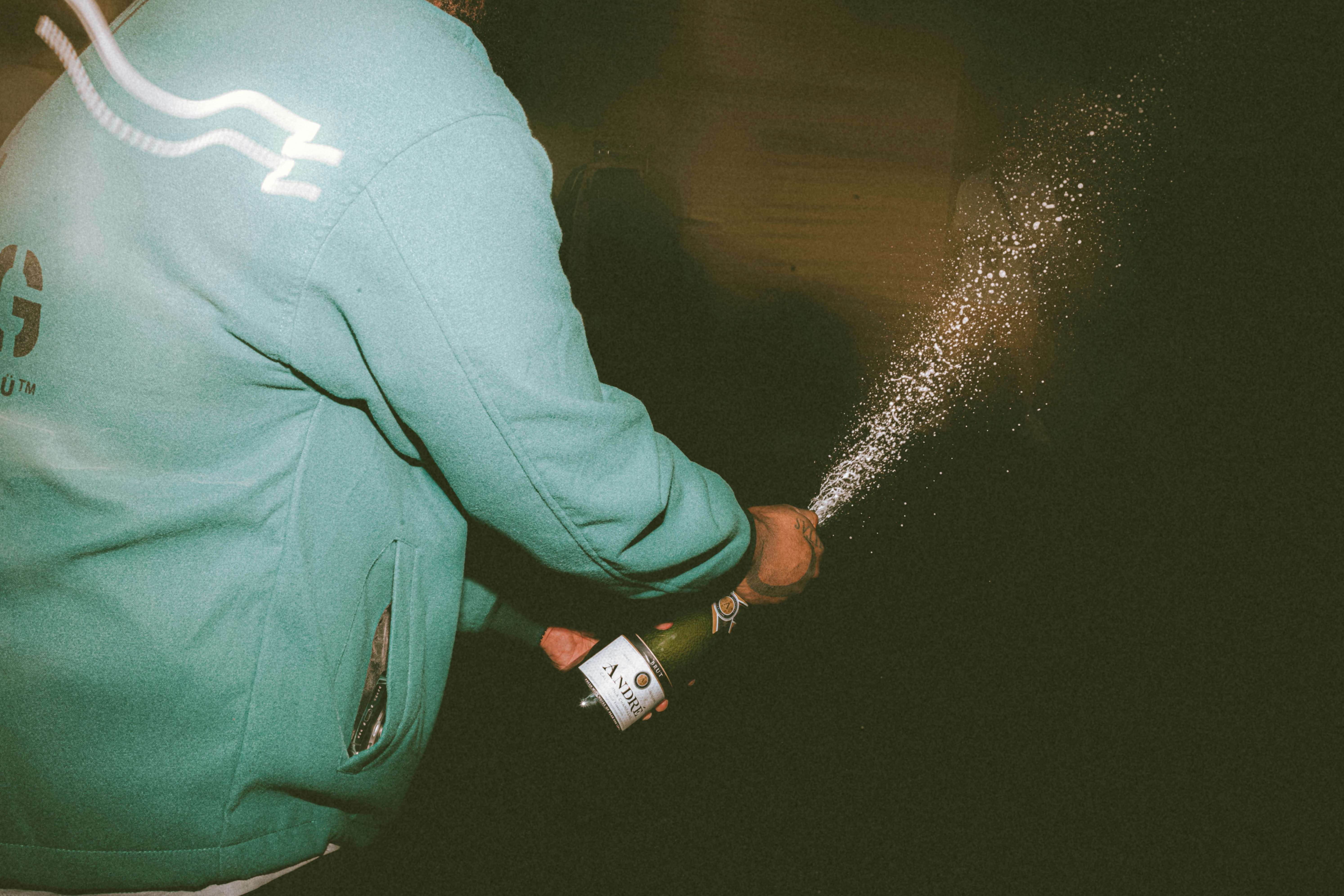 a man in a blue sweatshirt spraying water on his hands