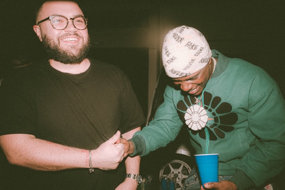 A friendly local business owner shaking hands with a happy customer in a neighborhood setting.