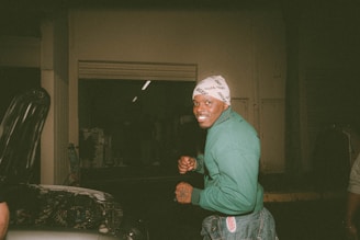 A friendly customer handing over a used car part to another person in a bright, welcoming workshop.