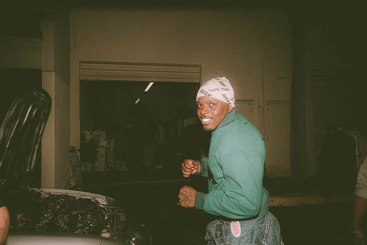 A smiling technician assisting a customer beside their car at dusk, with warm lighting.