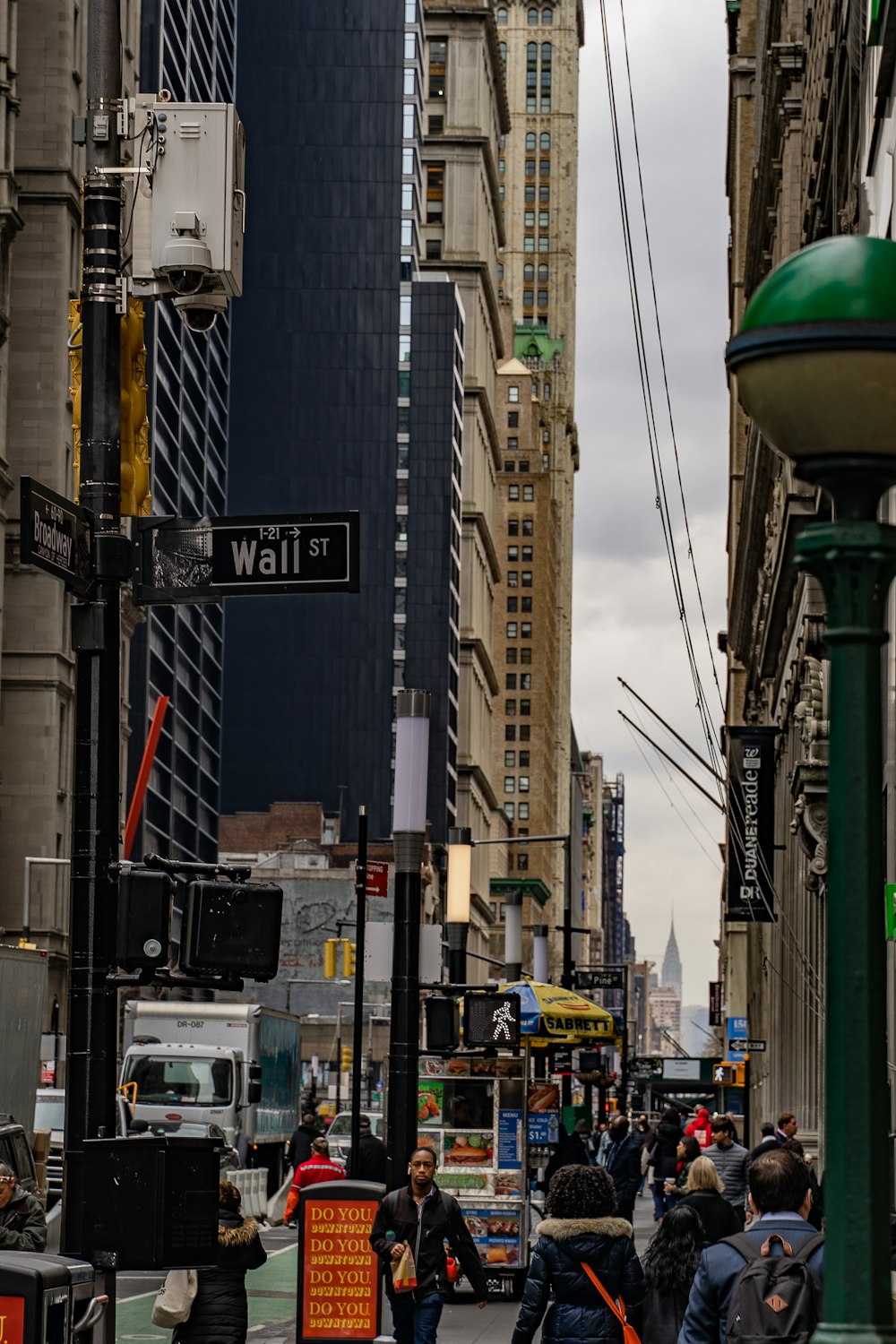 a group of people walking down a street next to tall buildings