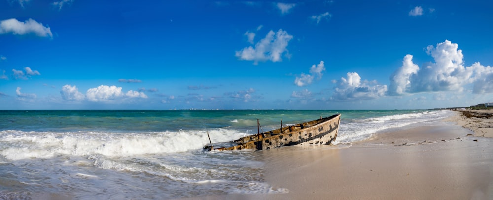 a boat sitting on top of a sandy beach next to the ocean