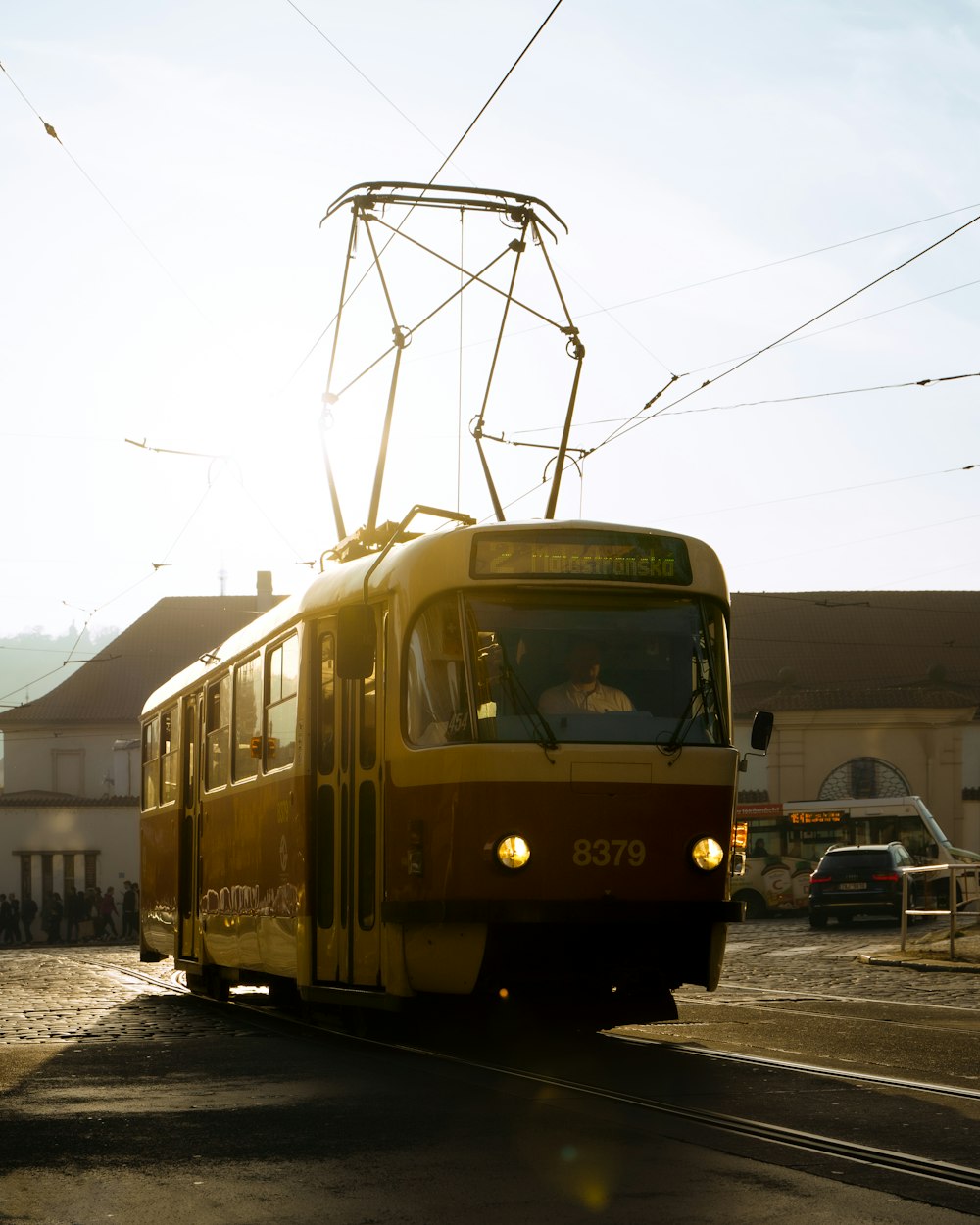 a yellow and red trolley traveling down a street