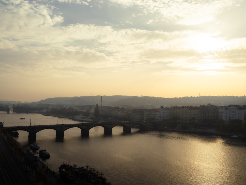 the sun is setting over a river and a bridge