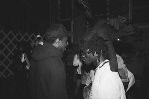 a black and white photo of two men talking