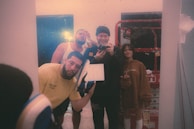 A group of friends laughing and taking full-length photos in front of the interactive mirror booth.