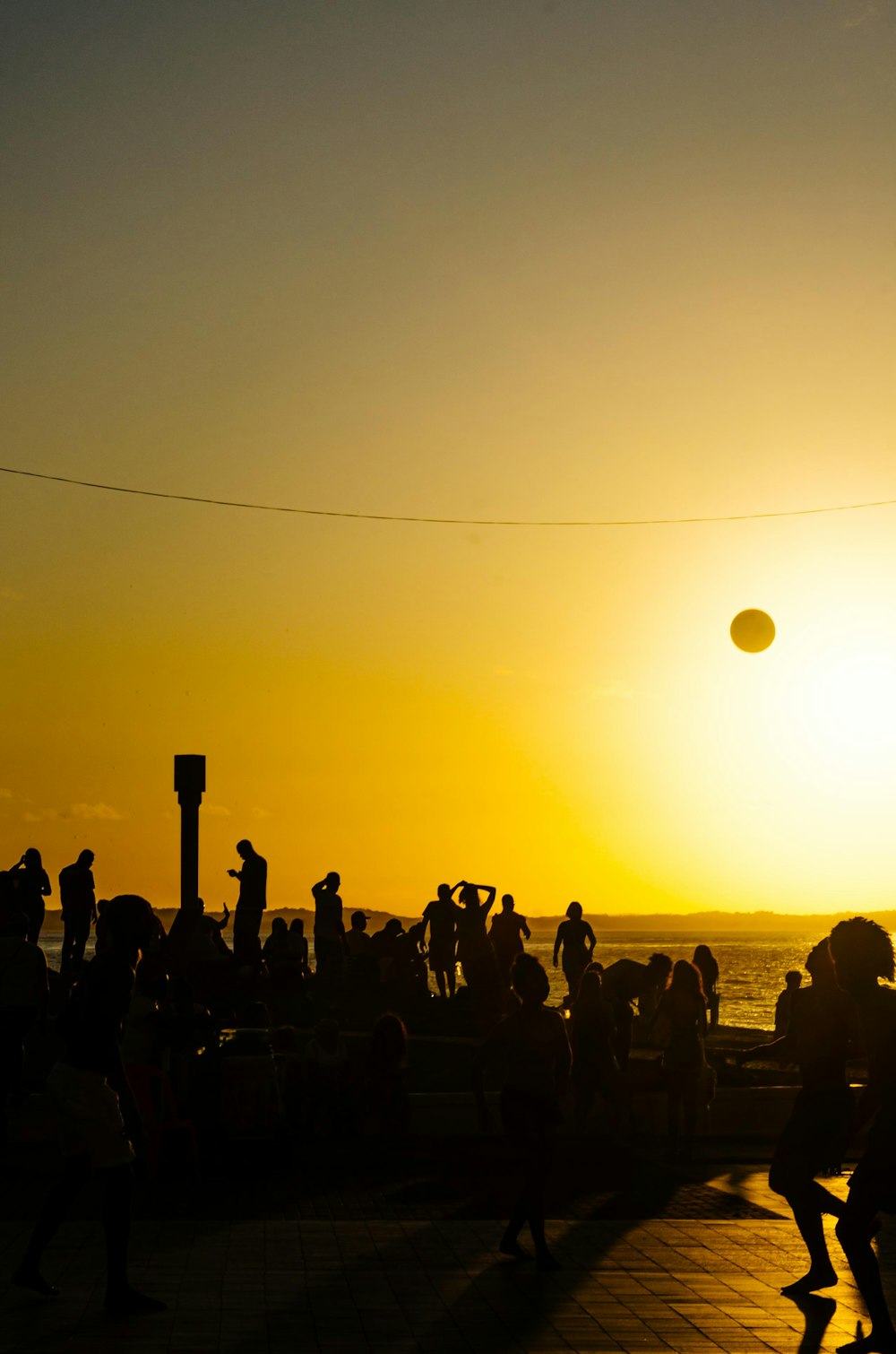 a group of people standing on top of a beach next to the ocean