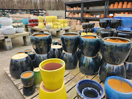 Display of colorful polyethylene pots lined up on wooden shelves.