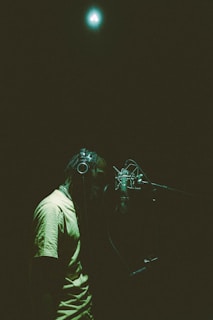 A candid shot of a singer recording vocals with headphones in a softly lit room