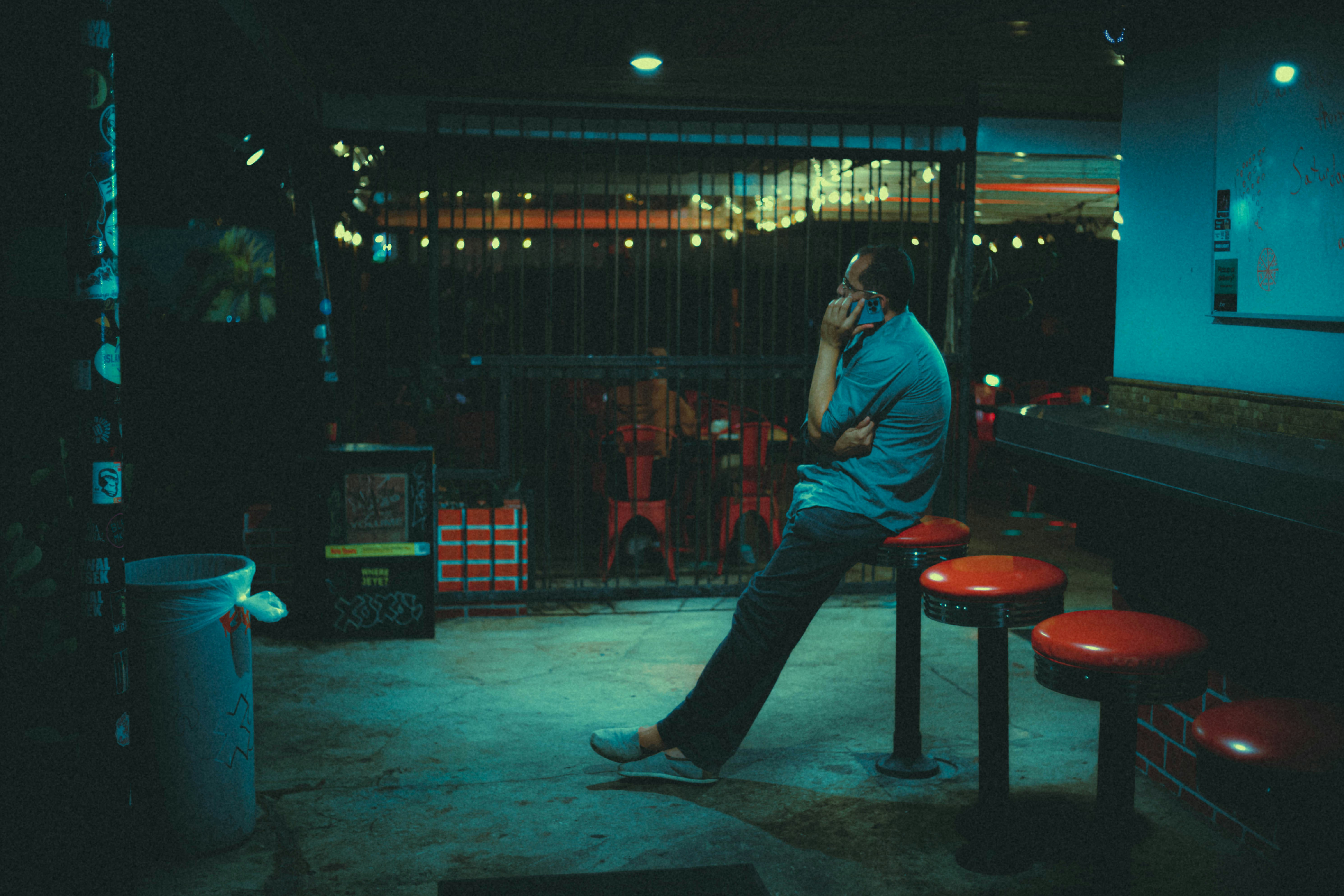 a man sitting on a stool talking on a cell phone (Photo by Frankie Cordoba on Unsplash)