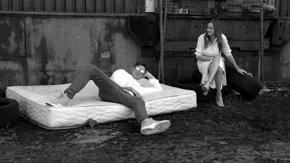 a man laying on a mattress next to a woman