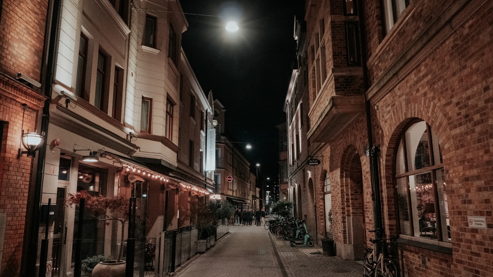 a narrow city street at night with lights on