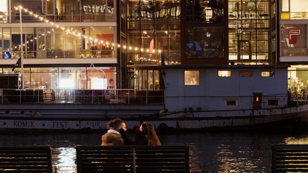 two people sitting on a bench in front of a building