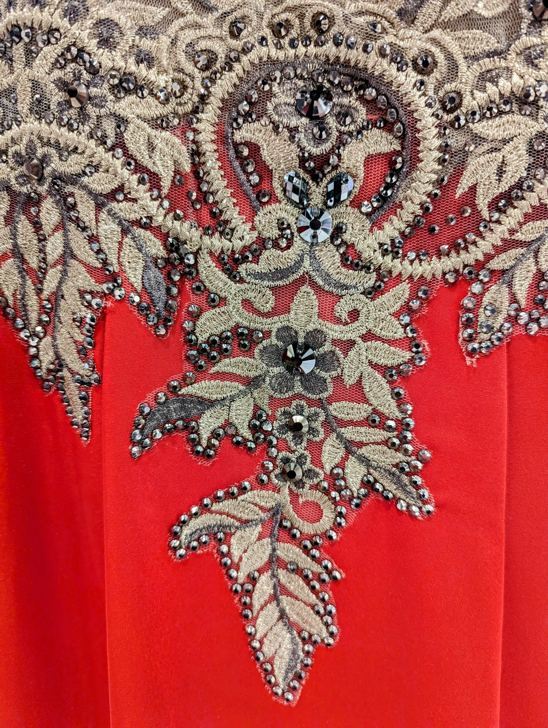 A finished vintage-style embroidered panel featuring a harmonious blend of gold and emerald threads on a deep burgundy background.