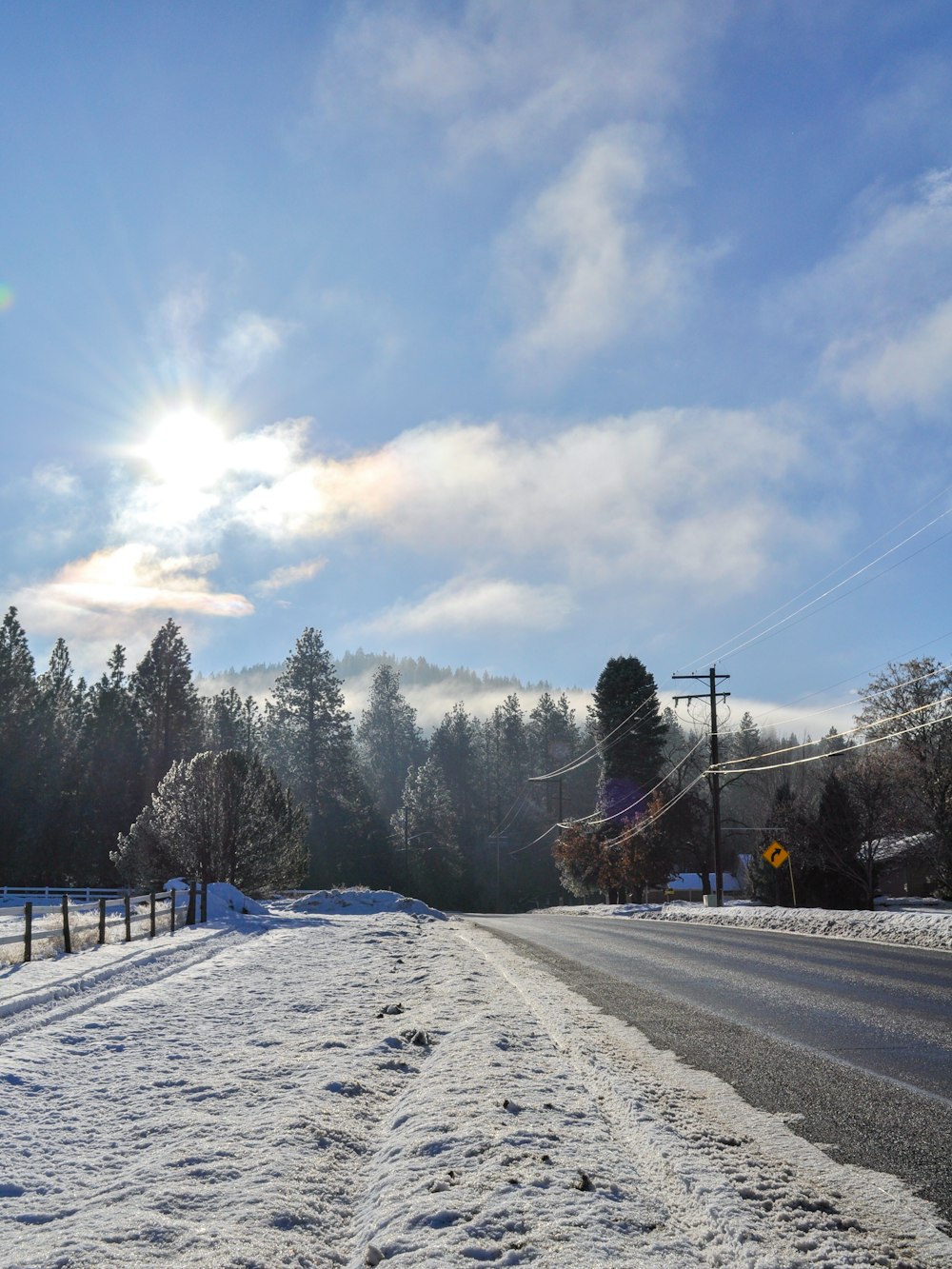 a road with snow on the side and trees on the other side