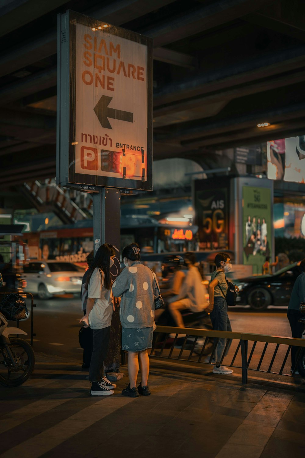 a group of people standing next to a street sign