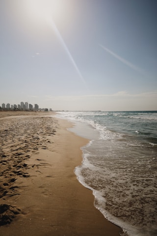 A sunny beach scene in São Paulo with waves gently crashing and people enjoying the shore.