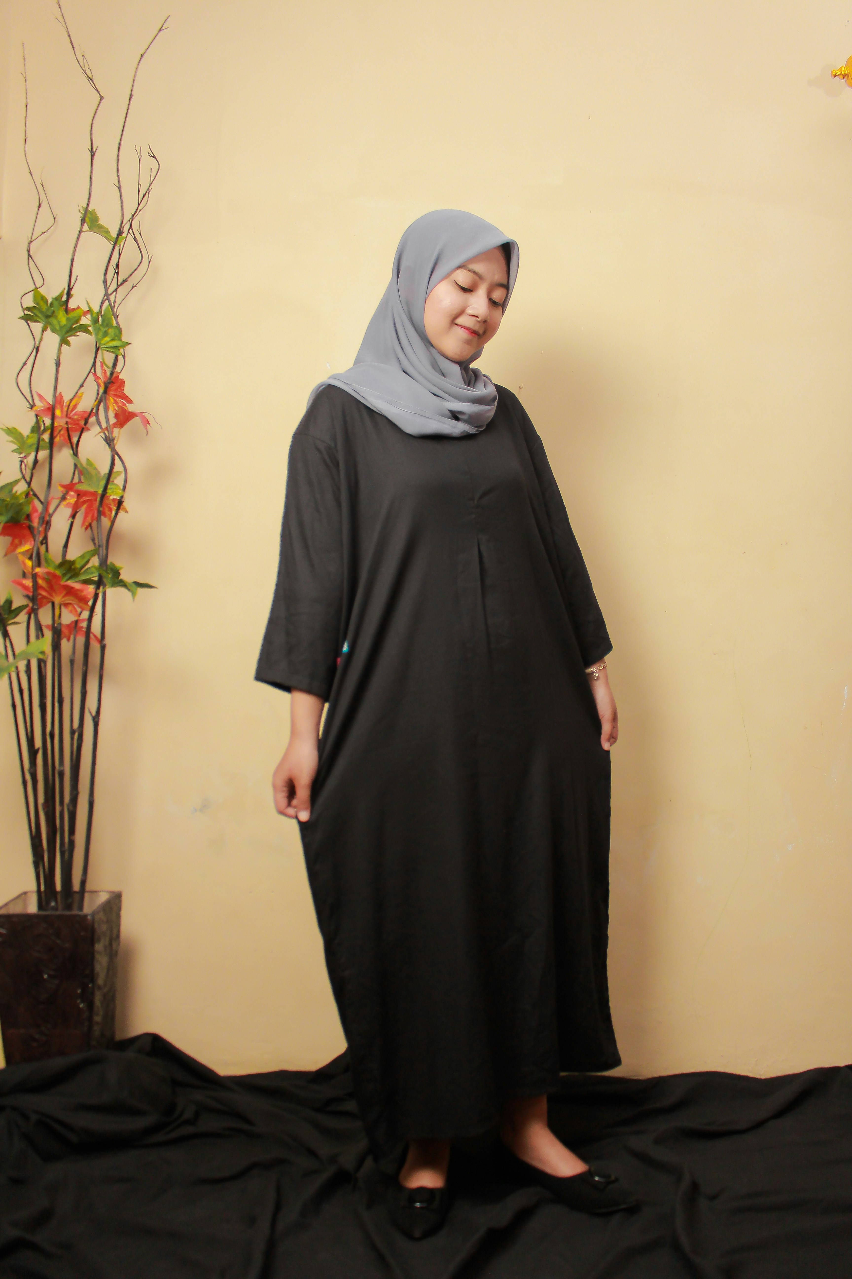 a woman in a black dress standing in front of a plant