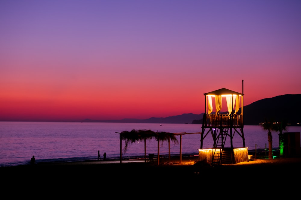 a lifeguard tower on a beach at sunset