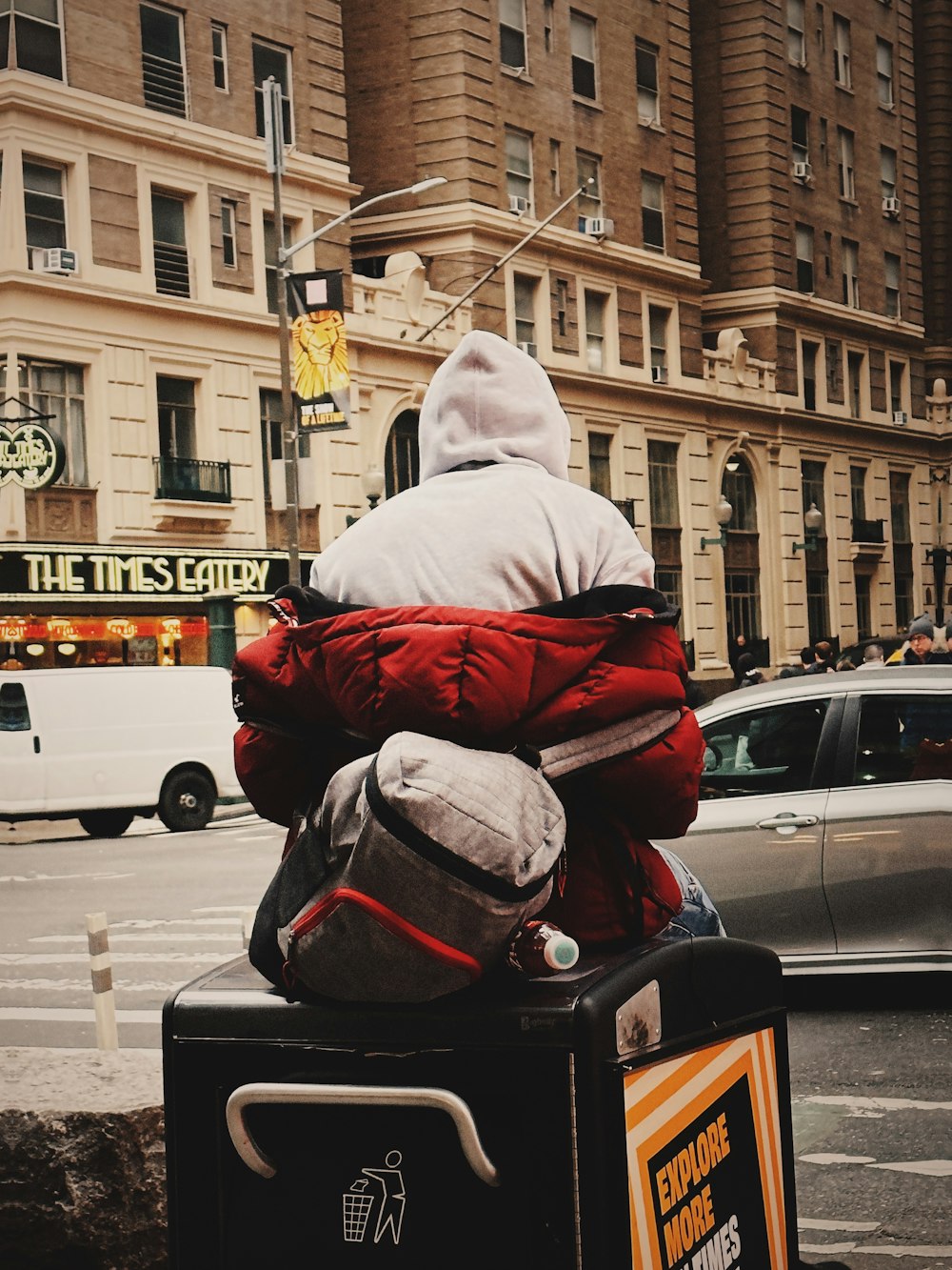 a person sitting on top of a suitcase on a city street