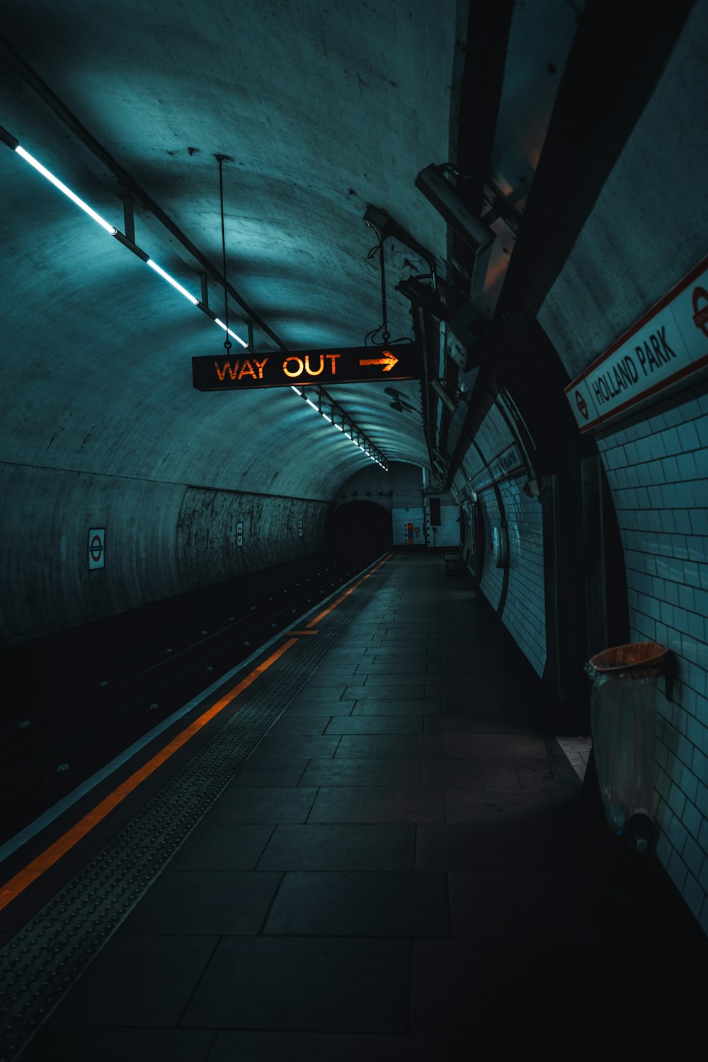 a subway station with a subway sign hanging from the ceiling