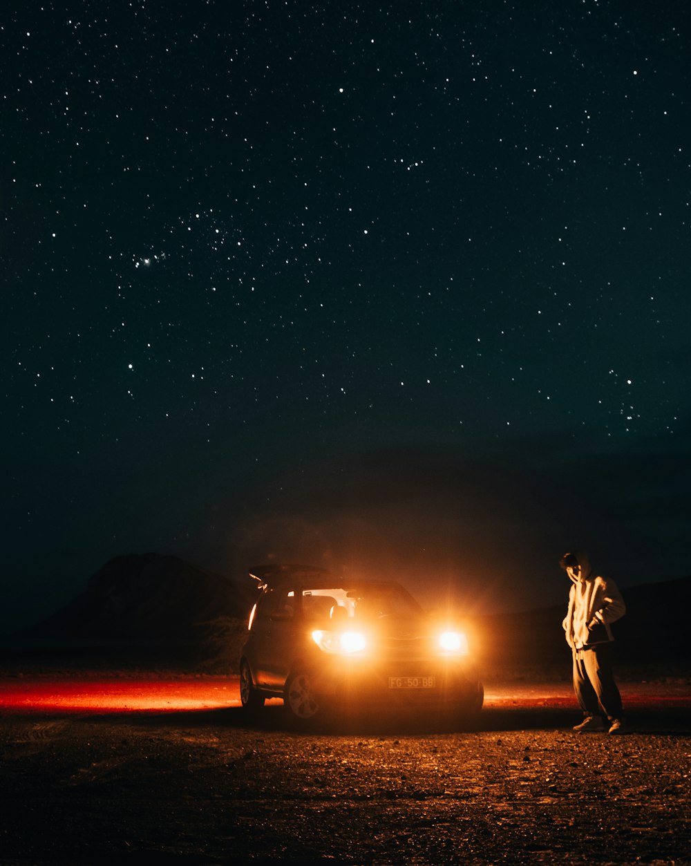 a man standing next to a car under a night sky
