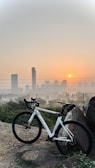 Side view of a sleek mountain bike on a rocky trail with Guangzhou skyline in background.