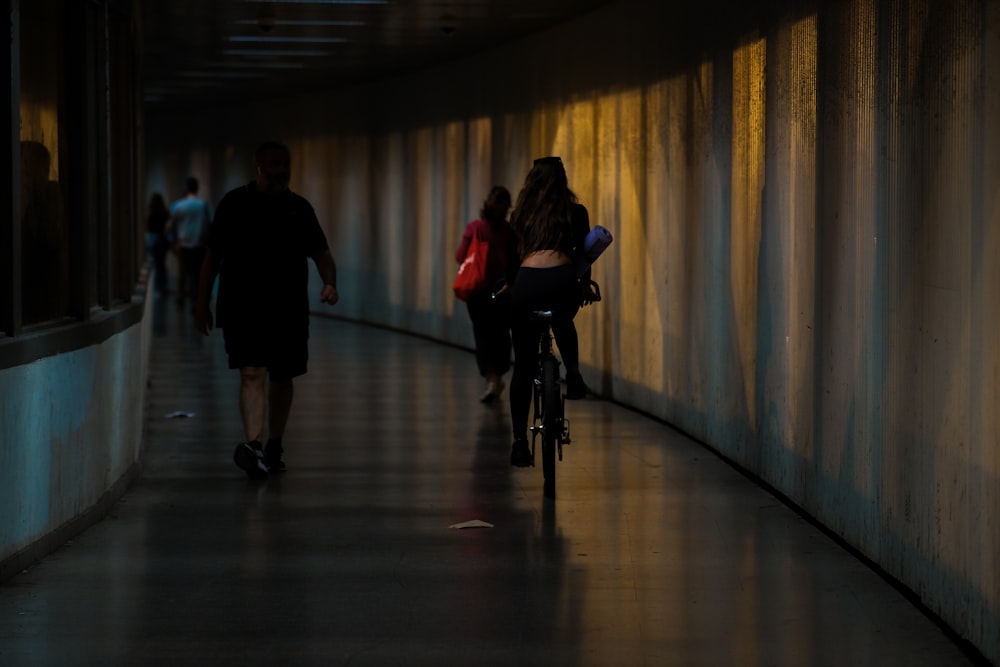 a woman riding a bike down a long hallway