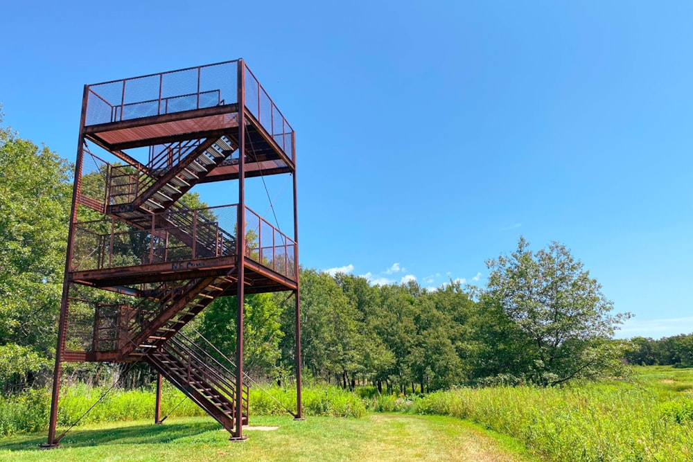 a tall metal tower sitting in the middle of a lush green field