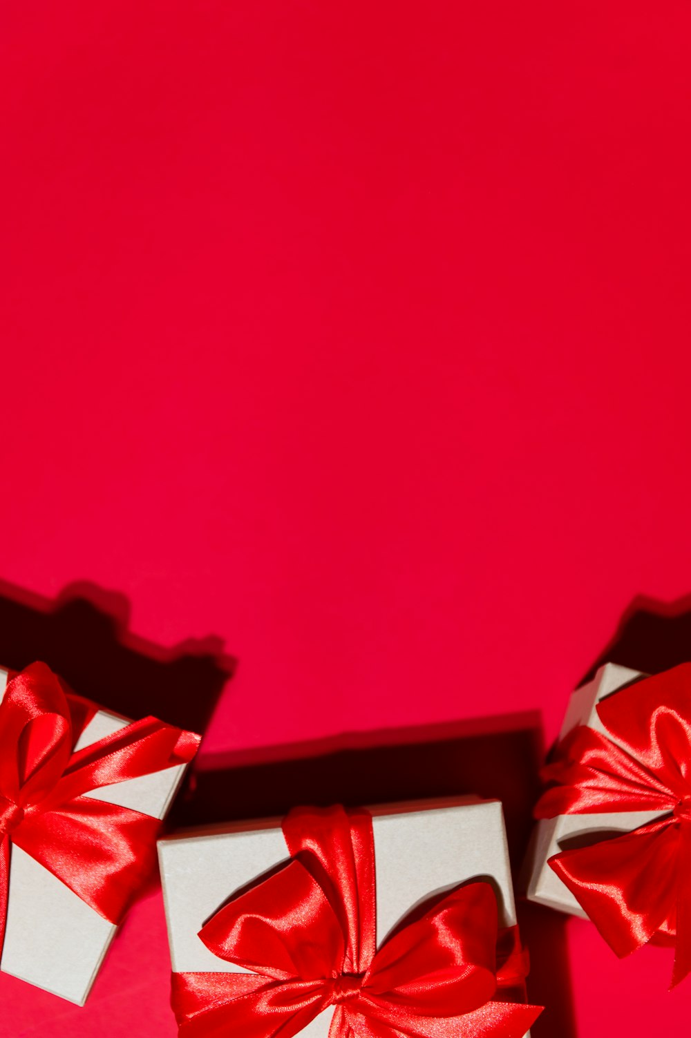 Due scatole bianche con fiocchi rossi su sfondo rosso