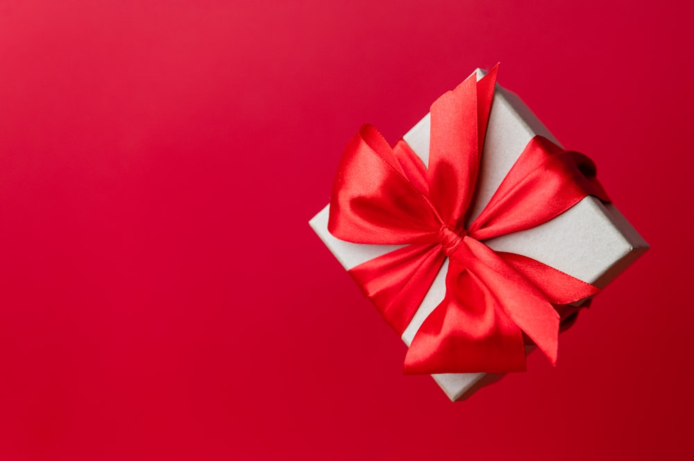 a white box with a red bow on a red background