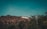 The image features the iconic Hollywood sign situated on a hilly landscape with a communication tower in the background. Trees frame the scene, with a clear sky overhead.