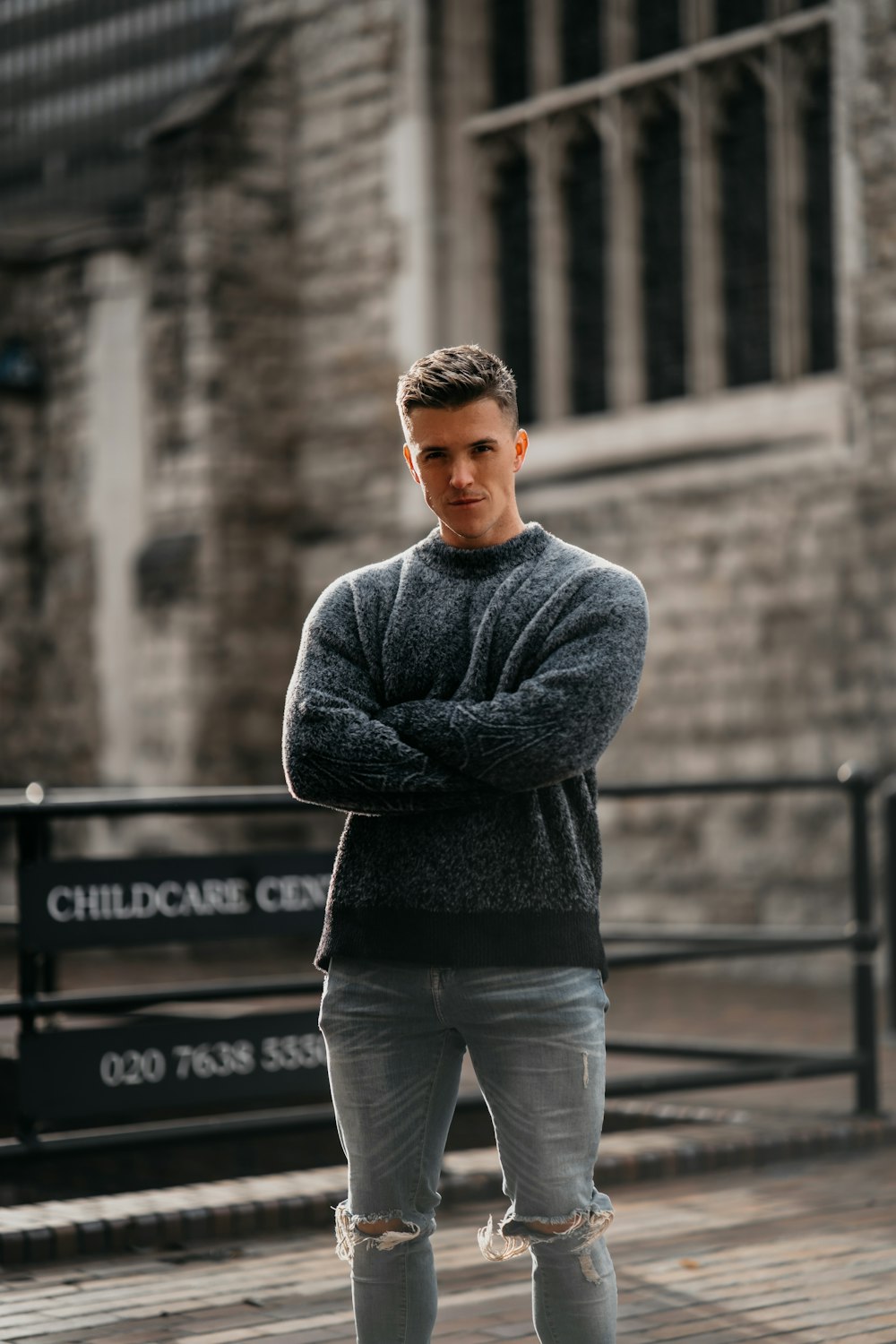 a man standing in front of a building with his arms crossed