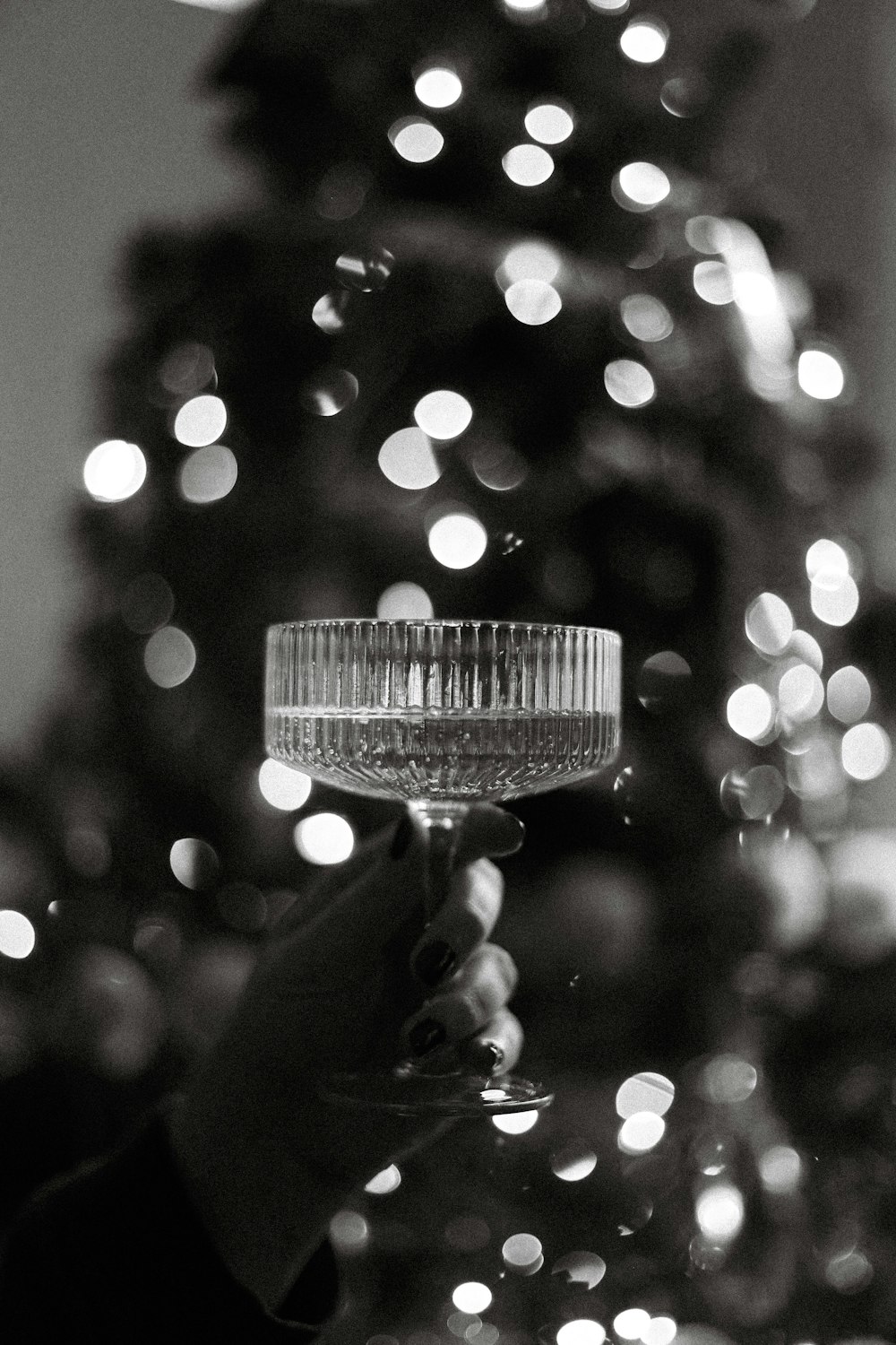 a person holding a wine glass in front of a christmas tree