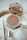 A luxurious arrangement of cosmetic products featuring a Gucci bronzer in an elegantly designed mirrored compact, surrounded by additional beauty items including a Dior compact and a small glass bottle. The setting has a sophisticated and stylish aesthetic with a marble surface.