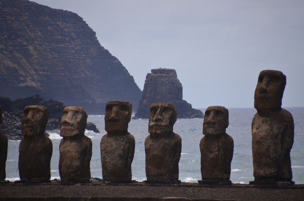 a row of statues sitting next to the ocean
