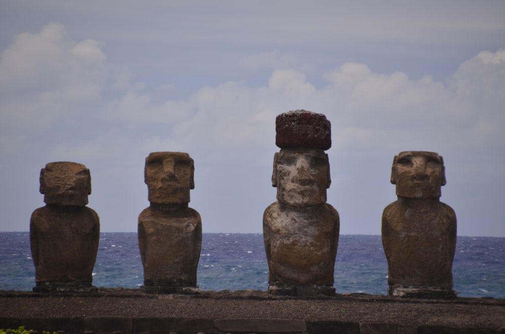 a row of statues sitting on top of a stone wall