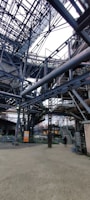 Wide shot of large steel framework undergoing surface treatment outdoors.