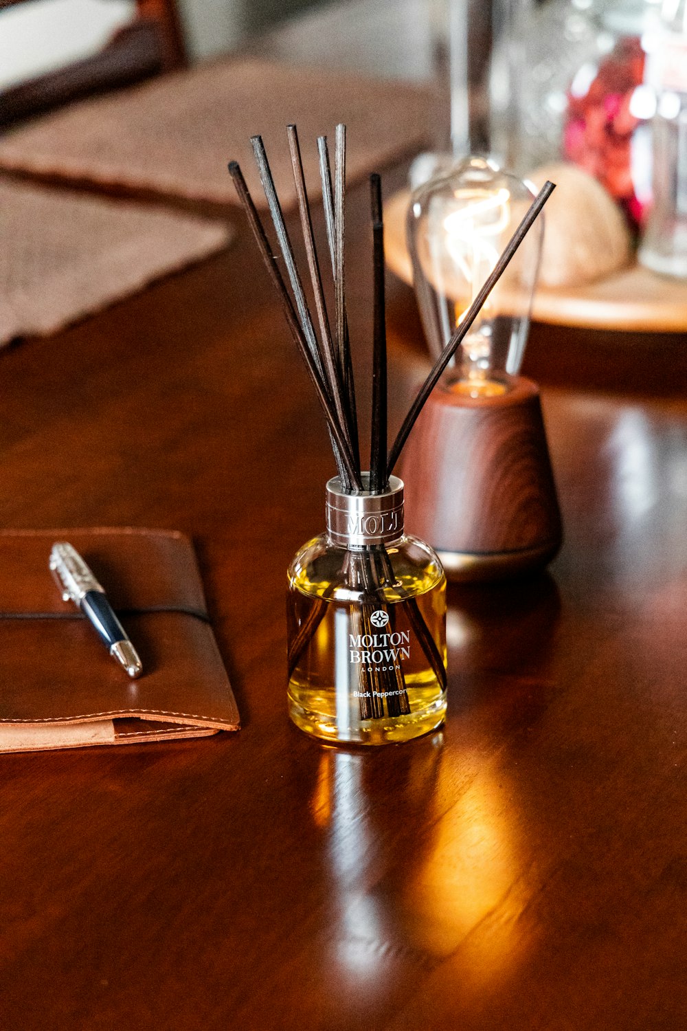 a wooden table topped with a bottle filled with reeds