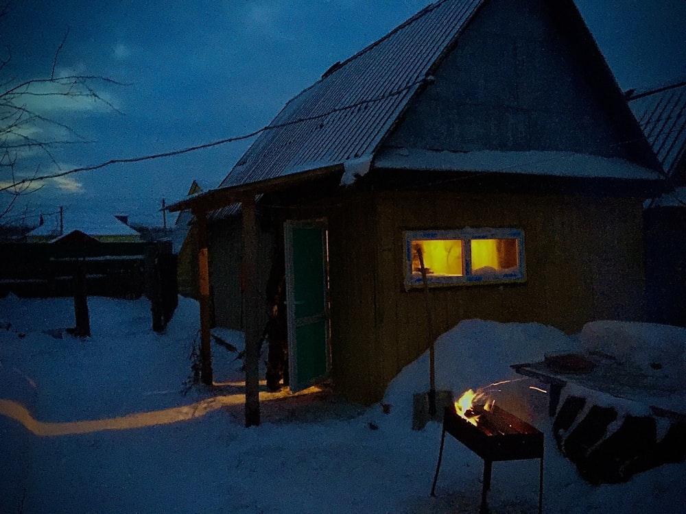 Una pequeña cabaña con un pozo de fuego en la nieve