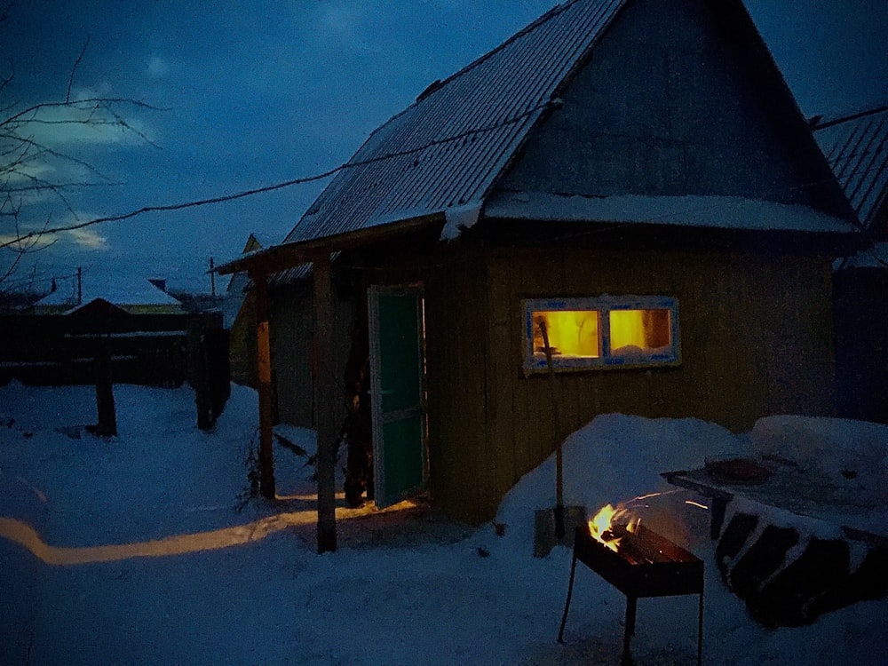 a small cabin with a fire pit in the snow