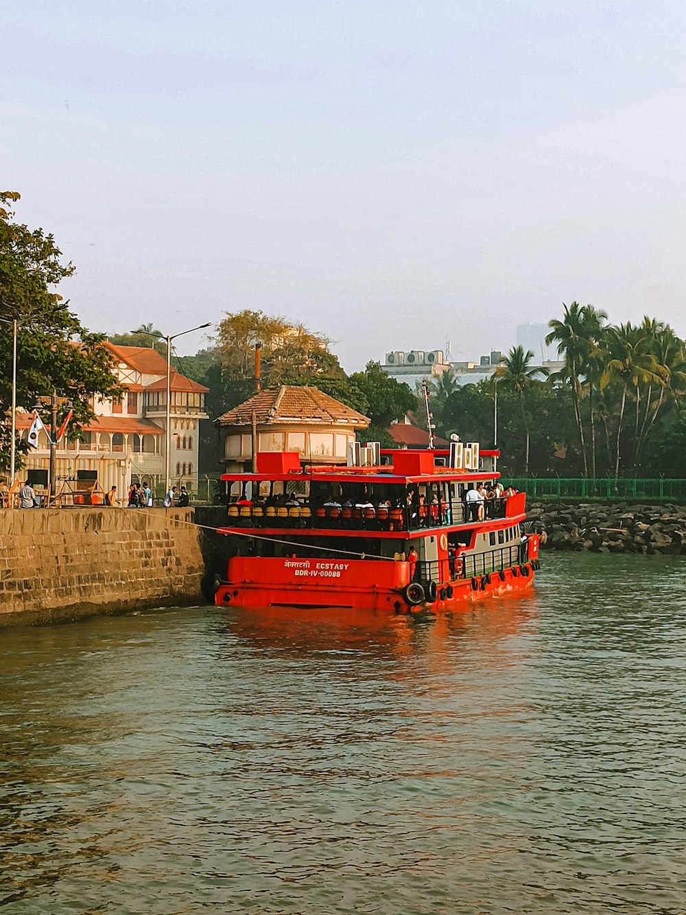 a red boat traveling down a river next to tall buildings