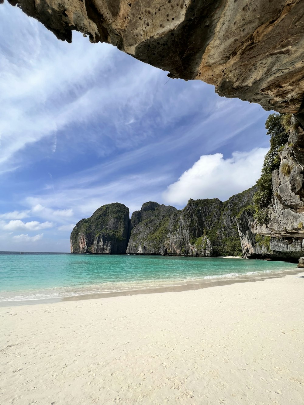 a beach with a rock formation and clear blue water