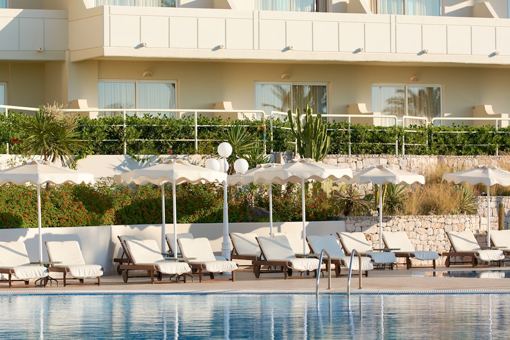 a row of lounge chairs sitting next to a swimming pool