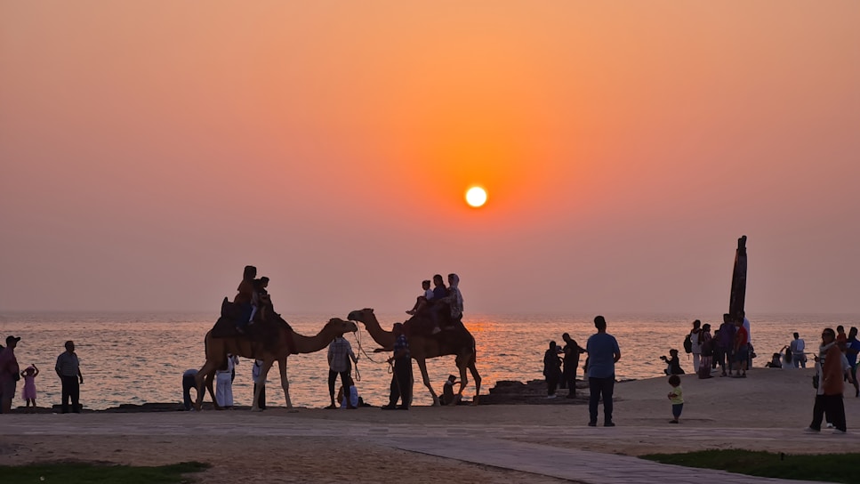 A vibrant sunset over the sand dunes of Rajasthan with camels silhouetted against the colorful sky.