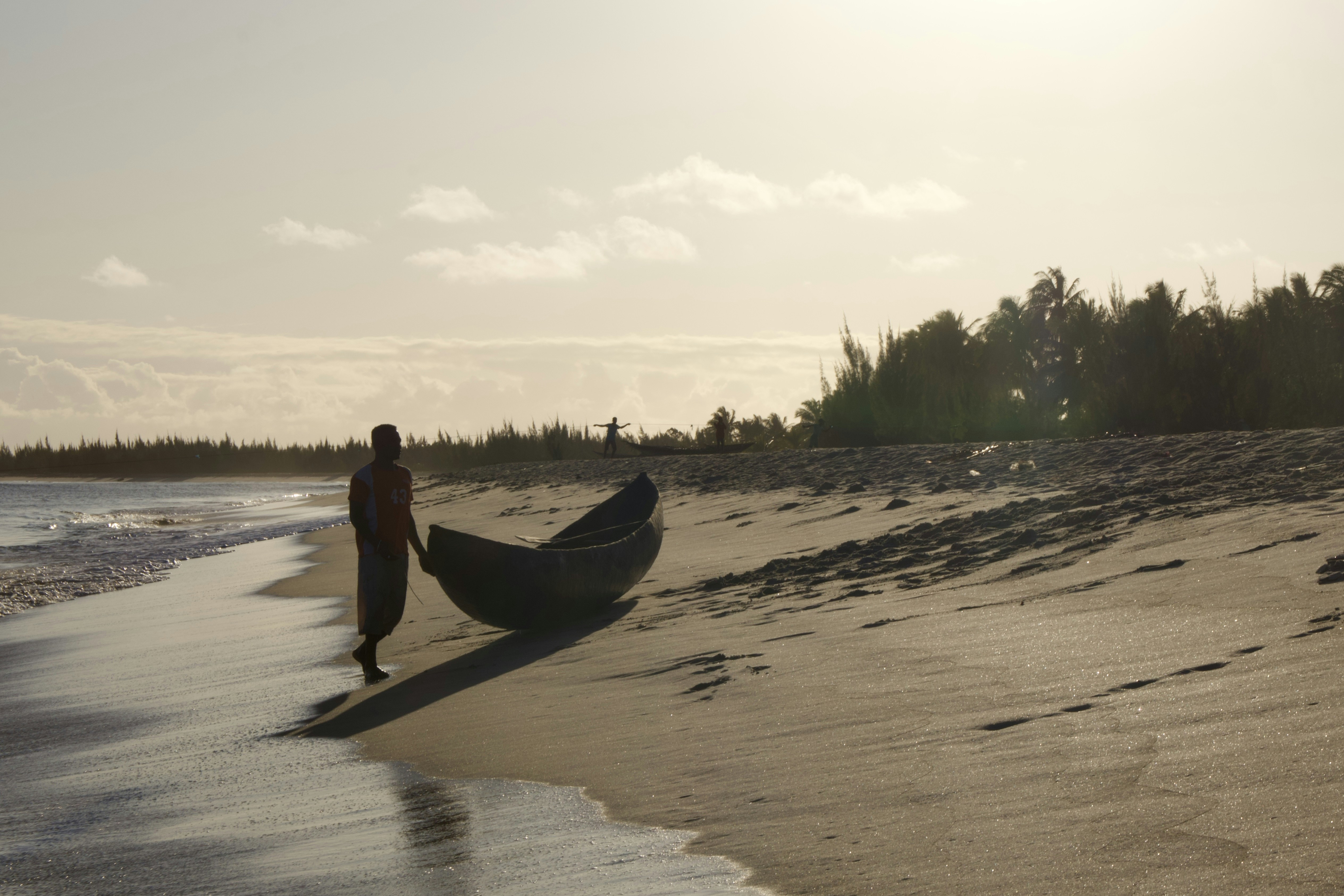 Ein Mann geht an einem Strand neben einem Boot spazieren