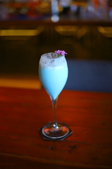Photo of a stylish blue and gold branded Aloha Drinks cocktail being served at a lively wedding reception in Goiás.