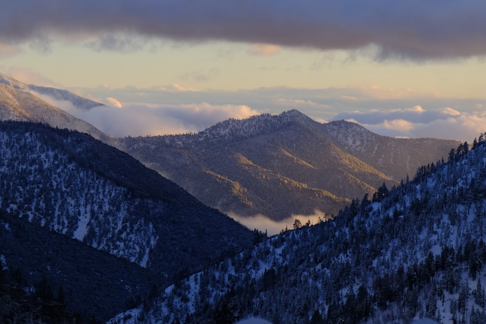 the mountains are covered in snow and clouds