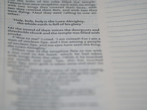 A close-up view of a page from a book, featuring a passage about the Lord Almighty. The text is focused on a specific verse, while additional text appears blurred in the foreground and background.