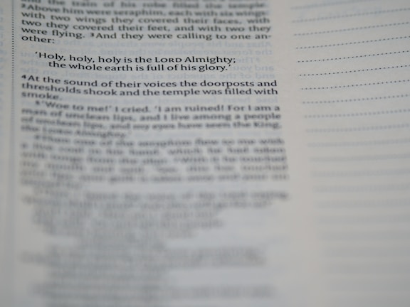 A close-up view of a page from a book, featuring a passage about the Lord Almighty. The text is focused on a specific verse, while additional text appears blurred in the foreground and background.